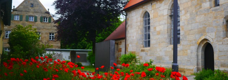 Rote Mohnblumenwiese vor Kirchengebäude