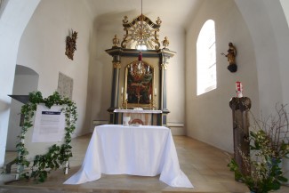 Blick aus den Kirchenbänken auf Altarraum mit stilisiertem Abendmahlstisch in St. Bartholomäus