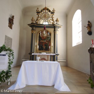 Blick aus den Kirchenbänken auf Altarraum mit stilisiertem Abendmahlstisch in St. Bartholomäus